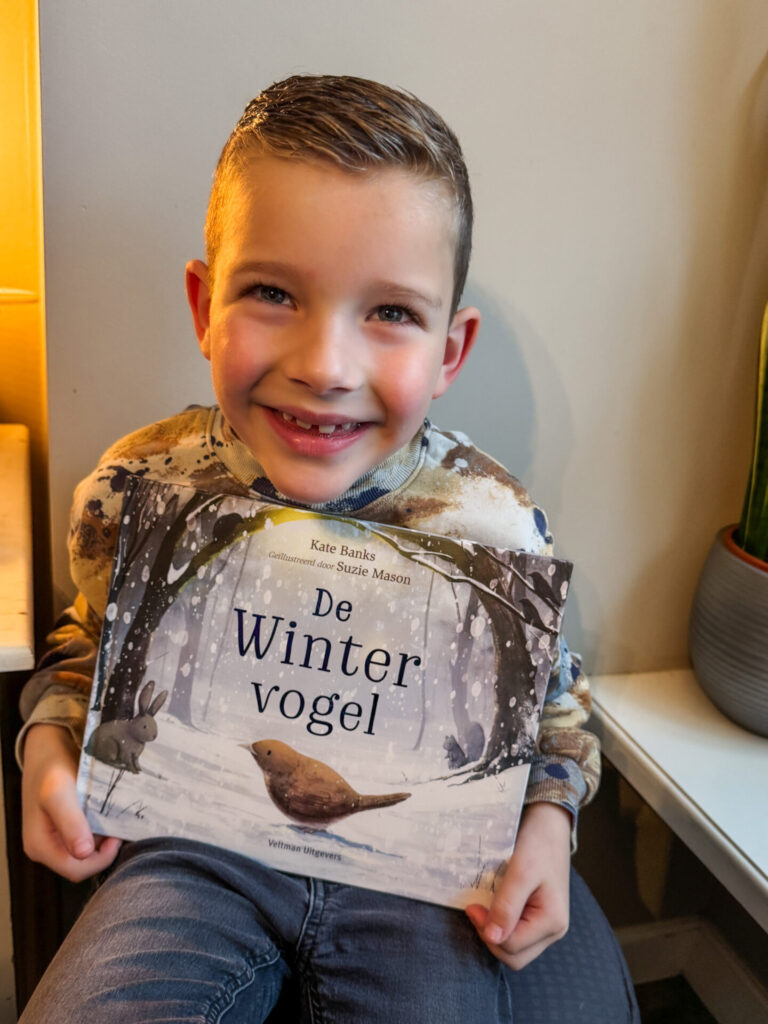 Kleine jongen op een stoel met een boek in zijn handen