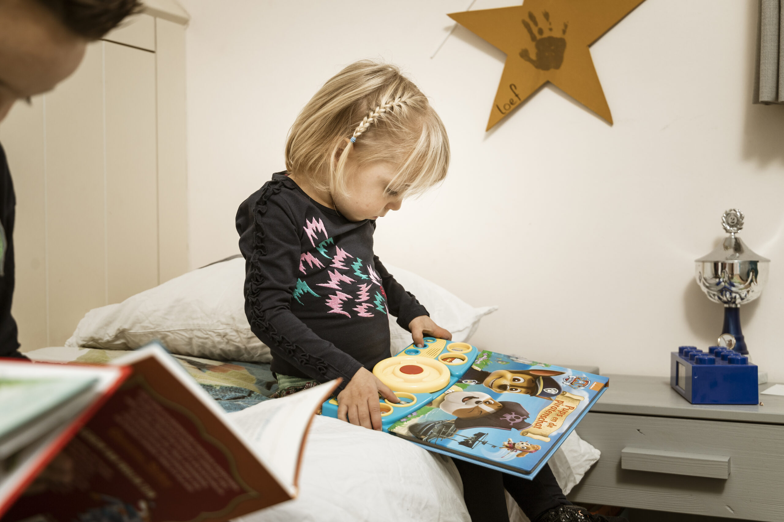 Jong meisje leest aandachtig een Paw Patrol-boek op bed, verdiept in een spannend dierenavontuur uit haar favoriete kinderboek.