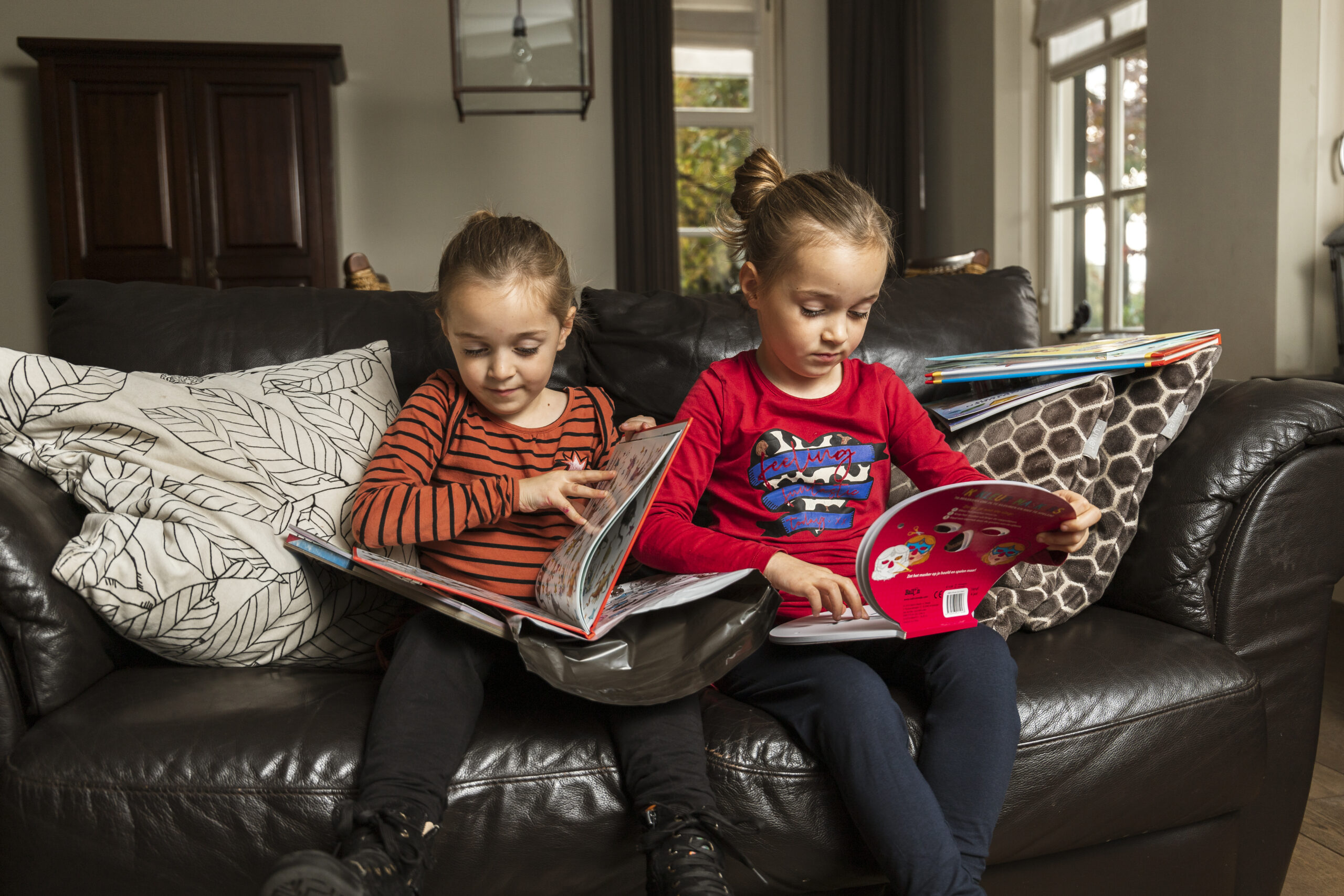 Twee kinderen lezen verdiept in avontuurlijke kinderboeken op de bank, klaar voor een verhaal vol spanning, fantasie en ontdekkingen.